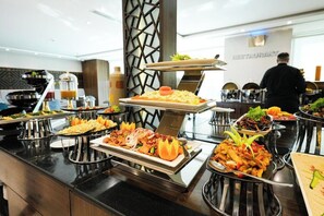 A buffet setup with various dishes, a person in the background, and a restaurant sign. - Elian Alsahafa Tower Hotel (Riyadh)