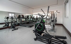 Une salle de sport équipée de tapis de course, de vélos elliptiques et de matériel de musculation.