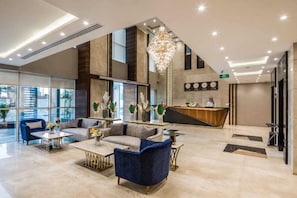 A modern lobby with a reception desk, sofas, a chandelier, and a large window. - Elian Alsahafa Tower Hotel (Riyadh)