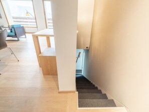 A staircase with a carpeted landing and a wooden floor, leading to a room with a desk and chair. - Casa Fau by Interhome (Laax)