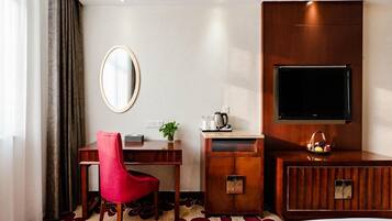 A hotel room with a bed, a desk with a chair, a TV, and a mirror.