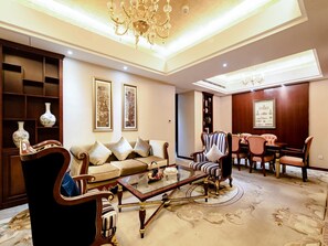 A spacious living room with a sofa set, a coffee table, a dining area with chairs, a chandelier, and wall art. - Madison Hotel Tai Mountain Scenic Spot (Tai'an)