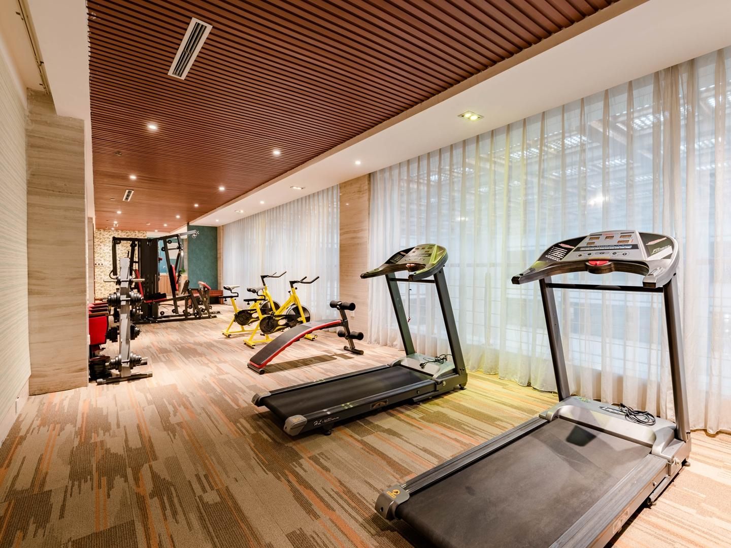 Un gimnasio con cintas de correr, bicicletas estáticas y máquinas de pesas.