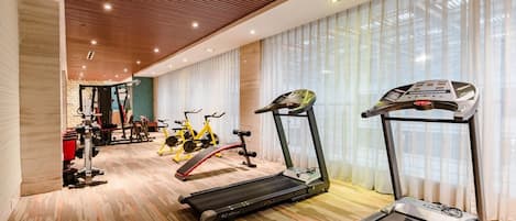 Un gimnasio con cintas de correr, bicicletas estáticas y máquinas de pesas.