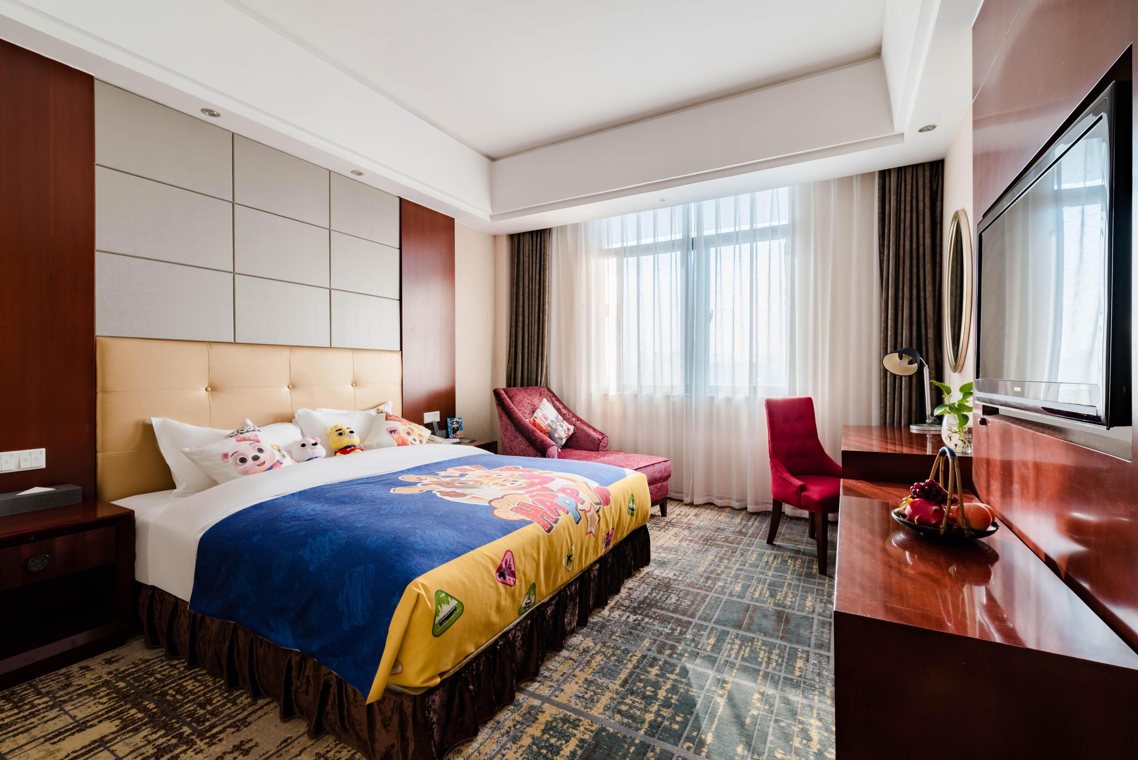 A hotel room with a large bed, a desk, a chair, and a TV.