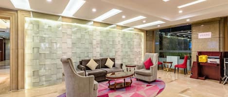 A lobby with a sofa set, a coffee table, a patterned wall, and a reception desk.