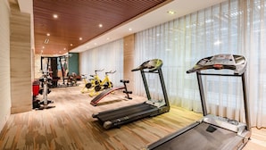 Un gimnasio con cintas de correr, bicicletas estáticas y máquinas de pesas.