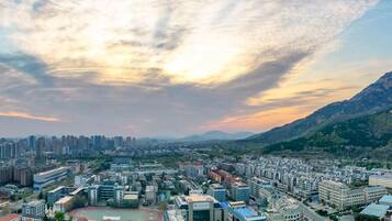 A cityscape with modern buildings, a large open square, and a mountain in the background.