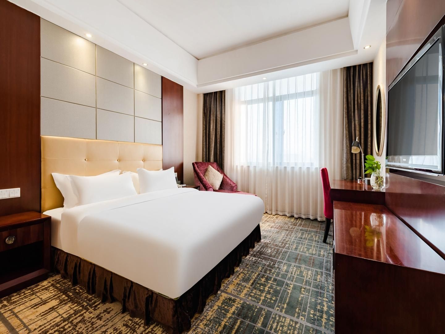 Una habitación de hotel con una cama grande, un escritorio, una silla y un televisor.