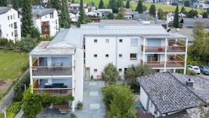 A multi-story residential building with balconies, a covered patio, and a small garden area. - Casa Miro Nr. 7 by Interhome (Flims)