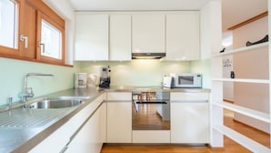 A modern kitchen with white cabinets, stainless steel appliances, and wooden flooring. - Casa Miro Nr. 7 by Interhome (Flims)