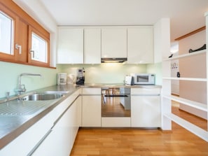 Een moderne keuken met witte kasten, roestvrijstalen apparatuur en houten vloeren.