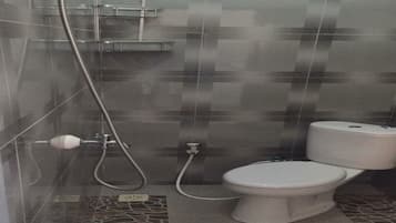 A bathroom with a toilet, a shower, and a tiled floor.