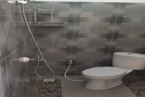 A bathroom with a toilet, a shower, and a tiled floor.