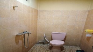 A small bathroom with a toilet, shower, and patterned floor tiles. - OYO 91230 Kelimutu Eco Village (Moni)