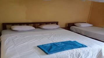 Une chambre d’hôtel avec deux lits, du linge de lit blanc et une serviette bleue sur le plus grand des lits.