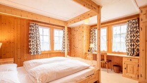 Una habitación de cabaña de madera con una cama, escritorio y ventanas.