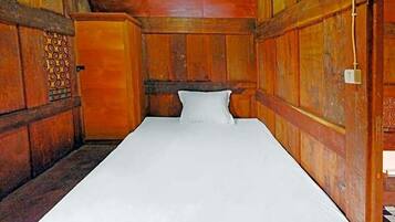 A single bed in a wooden room with a patterned wall and a door with a lock.