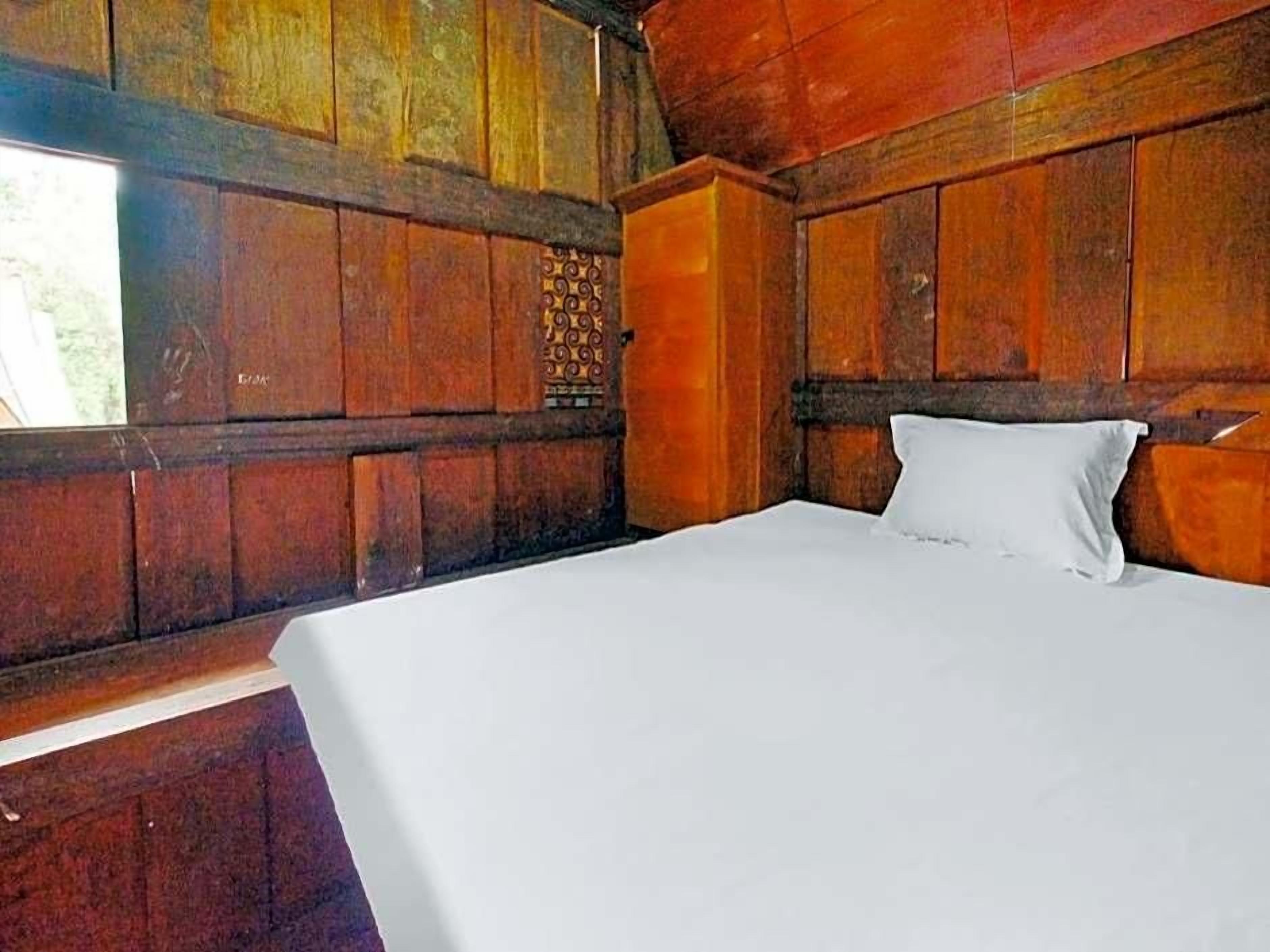 A wooden room with a bed, a window, and a wall with a decorative panel.