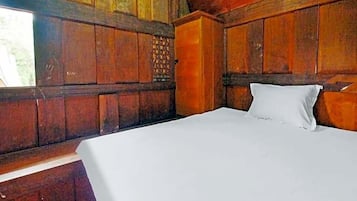 A wooden room with a bed, a window, and a wall with a decorative panel.