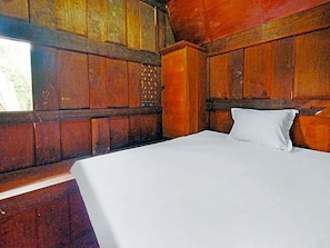 Una habitación de madera con una cama, un ventanal y un panel decorativo en la pared.