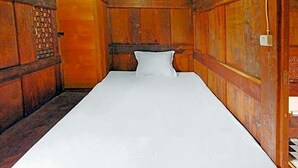 A single bed in a wooden room with a patterned wall and a door with a lock.