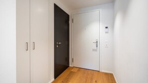 Ein Korridor mit Holzboden, weißen Wänden und einer schwarzen Tür.