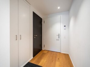 A hallway with a wooden floor, white walls, and a black door. - Vallada 14_01 by Interhome (Flims)