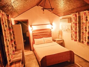 Un dormitorio con una cama de madera, una mesita de noche, una lámpara colgante y cortinas con motivos florales.