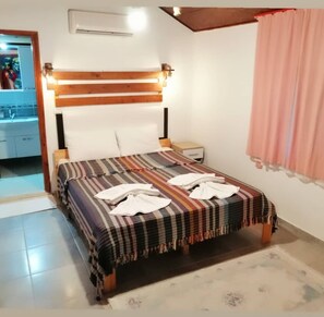 Un dormitorio con cabecera de madera, colcha a rayas y dos toallas sobre la cama.