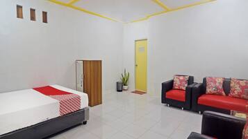 Habitación de hotel con cama, sofá, armario, puerta y planta en maceta.