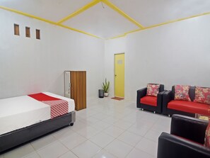 A hotel room with a bed, a sofa, a wardrobe, a door, and a potted plant. - OYO 91246 Pulisan Ekowisata Homestay (Manado)