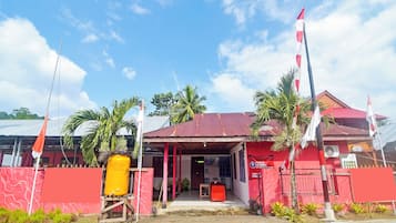 Un edificio con fachada roja, un vestíbulo cubierto y un letrero que indica que es un establecimiento comercial.
