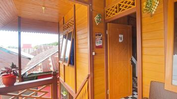 A wooden exterior with a balcony, a door with a sign, and a checkered mat at the entrance.