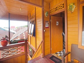 Esterno in legno con un balcone, una porta con un cartello e un tappetino a scacchi all'ingresso.