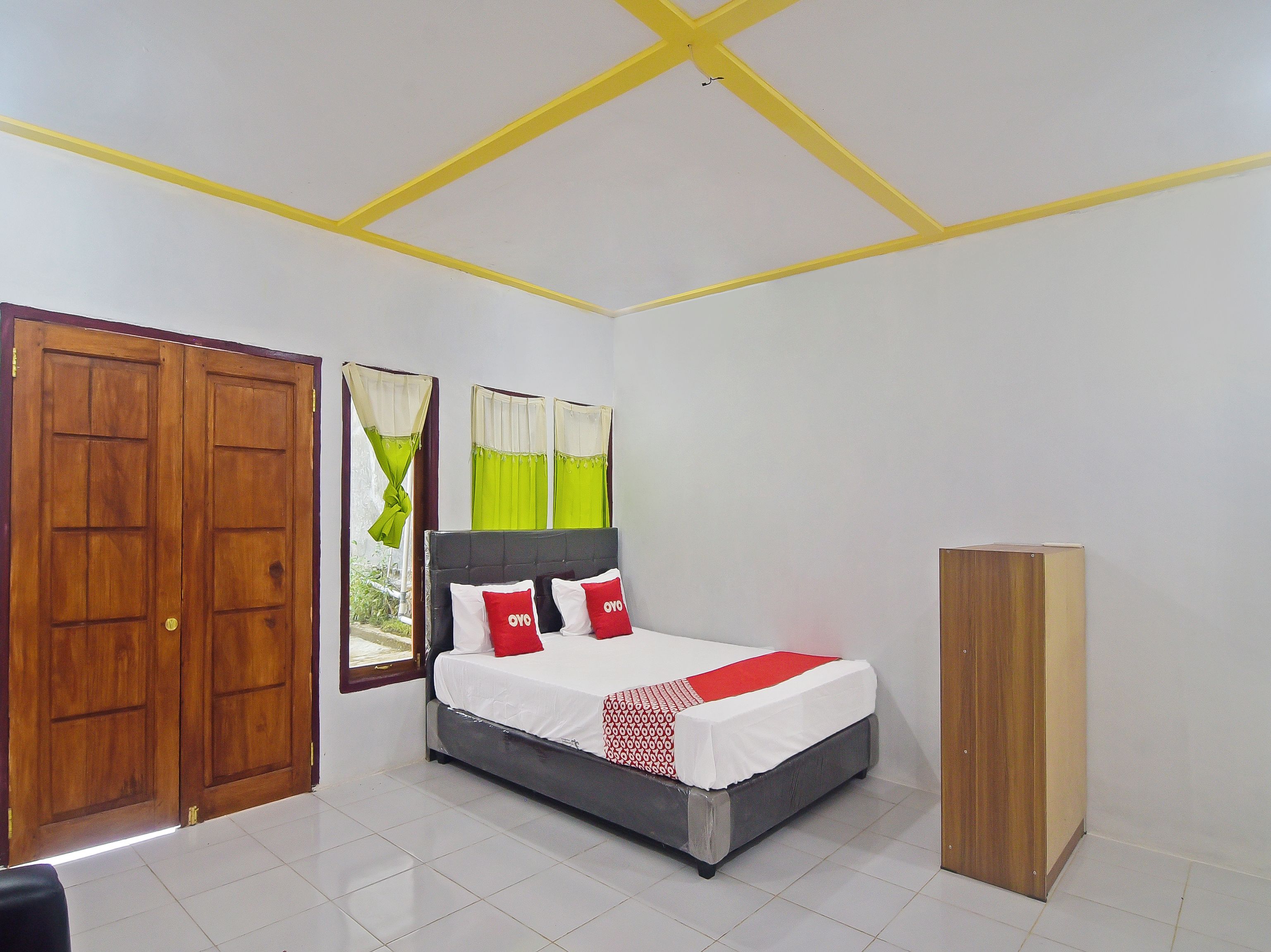 A bedroom with a bed, wooden wardrobe, and a window with curtains.