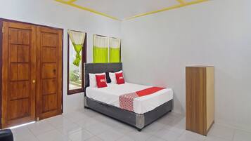 A bedroom with a bed, wooden wardrobe, and a window with curtains.
