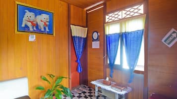 Una habitación con paredes de madera, suelo a cuadros, un cuadro enmarcado de gatos, un reloj y un letrero que indica el camino a la cocina.