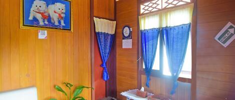A room with wooden walls, a checkered floor, a framed picture of cats, a clock, and a sign indicating the direction to the kitchen.