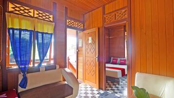 A room with a checkered floor, a sofa, a bed with pillows, and a wooden door.