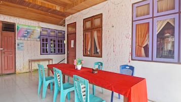 Un comedor con una larga mesa roja, sillas azules y un techo de madera.