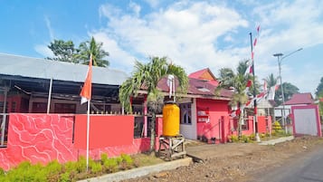 Un edificio con fachada roja, un tanque de agua amarillo y varias banderas.
