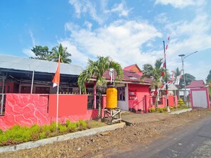 A building with a red exterior, a yellow water tank, and multiple flags. - OYO 91246 Pulisan Ekowisata Homestay (Manado)