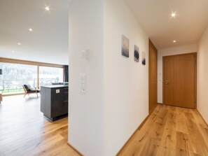 Ein modernes Interieur mit Küchenzeile, Holzboden und Blick durch große Fenster.