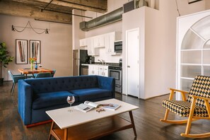 A modern living room with a blue sofa, a wooden coffee table, and a rocking chair. - Reside Houston Downtown A Wyndham Residence (Houston)