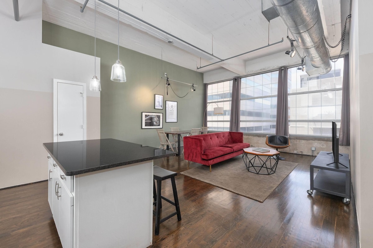 A modern apartment with a kitchen island, a red sofa, and a dining area.