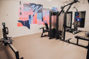 A gym with exercise equipment, a wall with abstract art, and a mirror. - Reside Houston Downtown A Wyndham Residence (Houston)