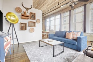 Un salon avec un canapé bleu, une table basse, un lampadaire et des éléments de décoration murale, notamment une tête de taureau et des tableaux encadrés.