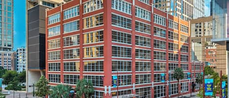 A multi-story hotel with a red facade, large windows, and a street view.