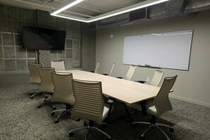 A conference room with a long table, six chairs, a whiteboard, and a flat-screen TV mounted on the wall. - Reside Houston Downtown A Wyndham Residence (Houston)